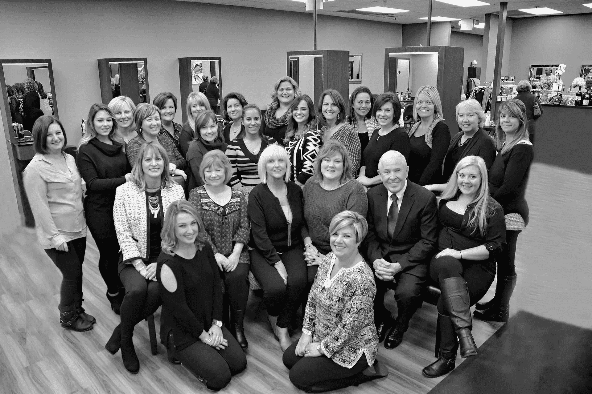 Group of smiling people posing in a salon-like setting.