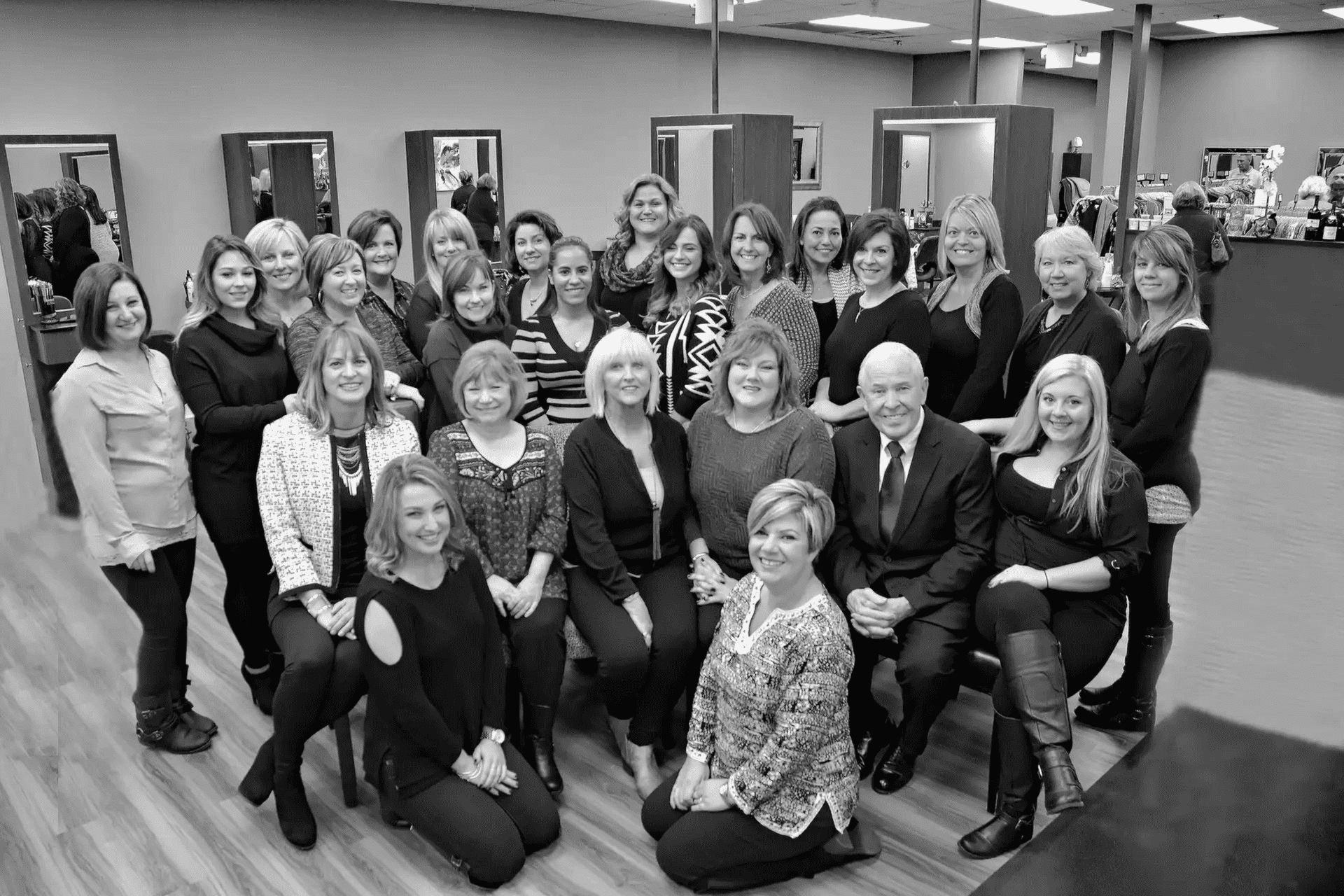 Group of smiling people posing in a salon-like setting.